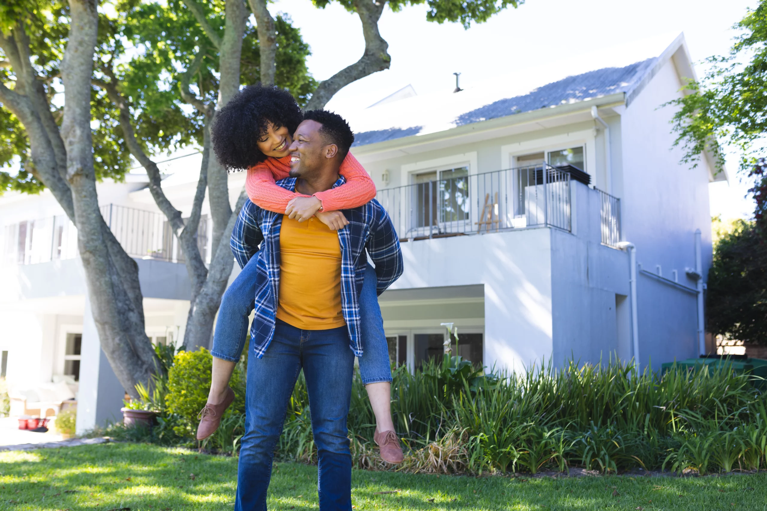 Happy couple in front of their home, illustrating homeowners insurance coverage and protection in Georgia.